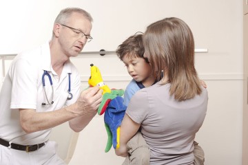 Das Bild zeigt einen Arzt und eine Mutter mit Kind.
