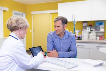 Eine Ärztin im Gespräch mit einem Patienten, beide sitzen sich gegenüber