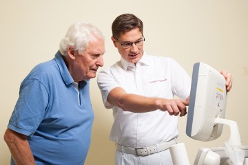 ein Arzt erklärt einem älteren Patient am Bildschirm die Diagnose