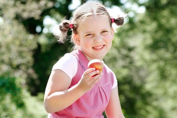 Auf dem Bild sieht man ein Mädchen mit einem Pfirsich in der Hand.
