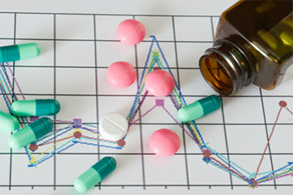 grüne, rosa und weiße Tabletten ausgekippt auf einem Blatt mit Diagrammen